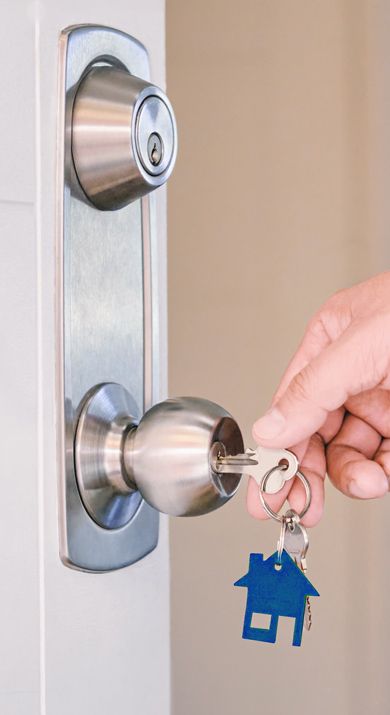 A Homeowner Is Inserting A Key Into The Doorknob Lock.