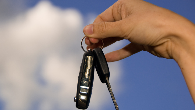 A Person Is Holding Two Car Keys In Their Hand.